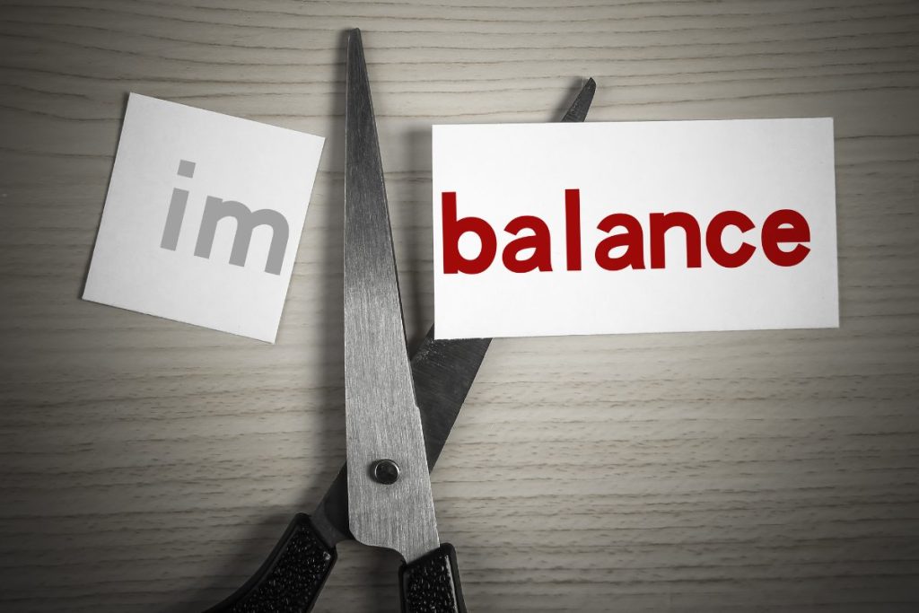 imbalance written on a piece of paper being cut between im and balance
