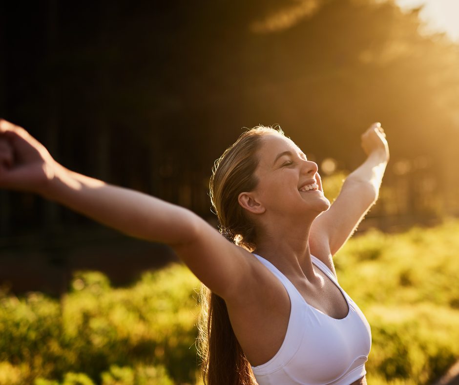A happy lady in the sunshine holding out her arms, feeling great and free. 